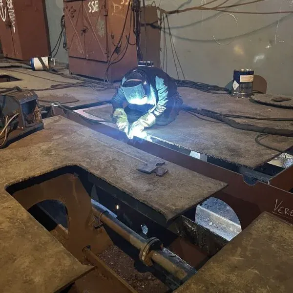 Welder performing structural steel welding on a ship double-bottom section