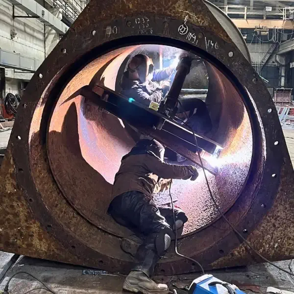 Welders performing internal structural welding inside a large-diameter steel component